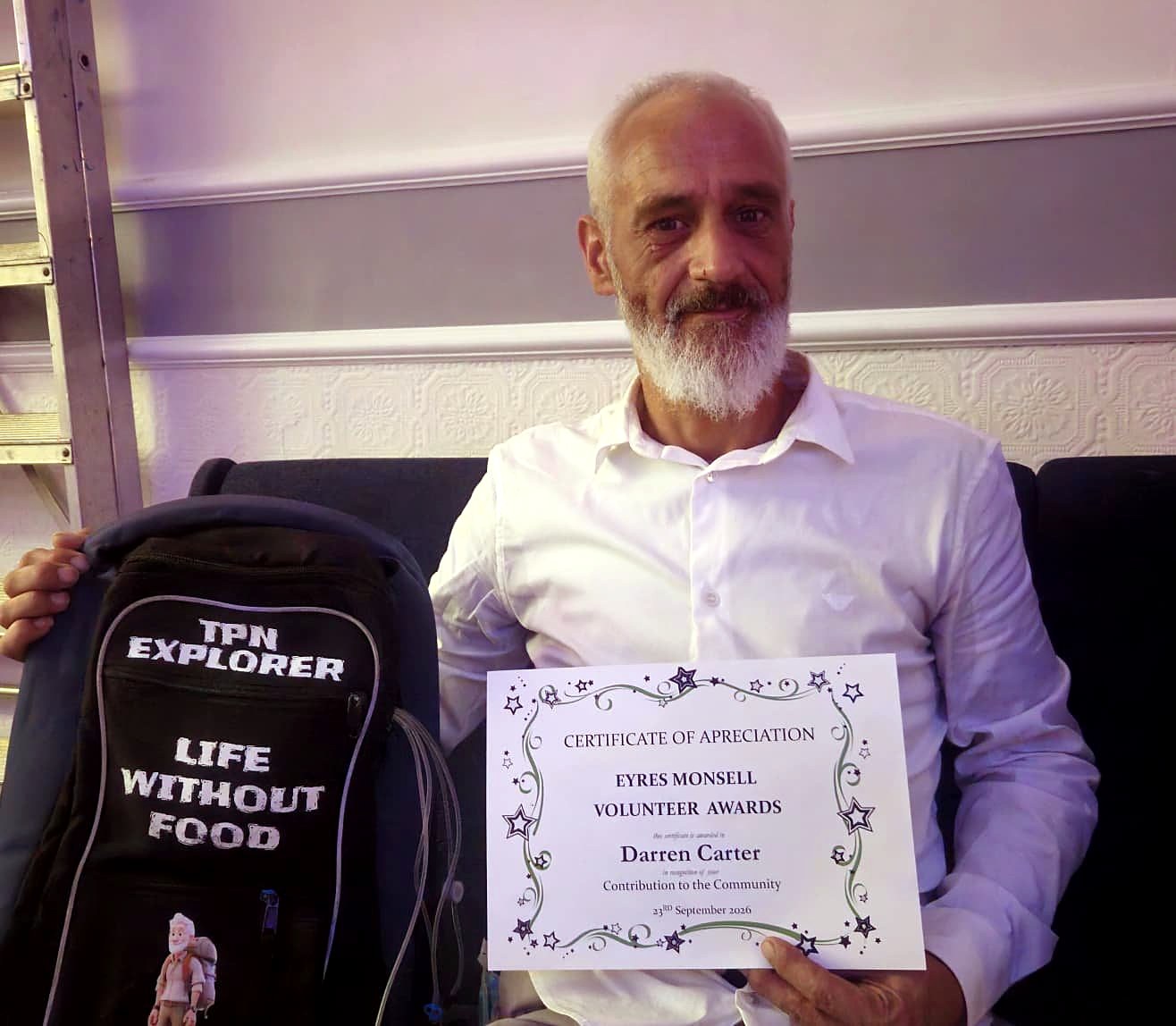Darren Carter holding his Certificate of Appreciation from the Eyres Monsell Volunteer Awards, 23 September 2026, beside his TPN Explorer backpack